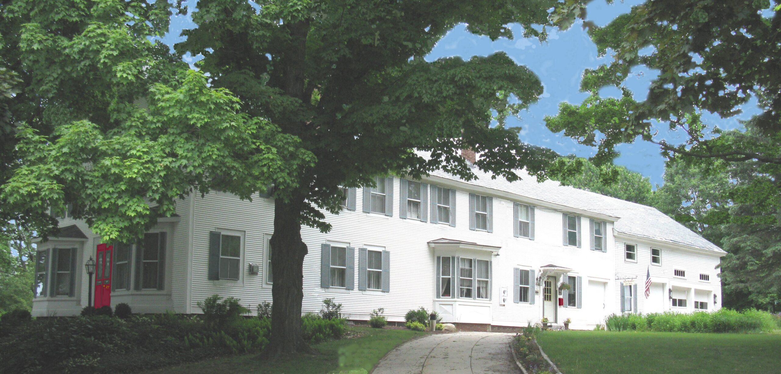 Large white house surrounded by green grass and trees